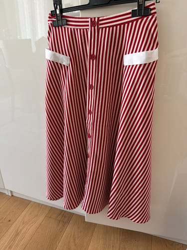 Photo d'un client de la jupe rouge à rayures boutonnées, suspendue à un cintre.