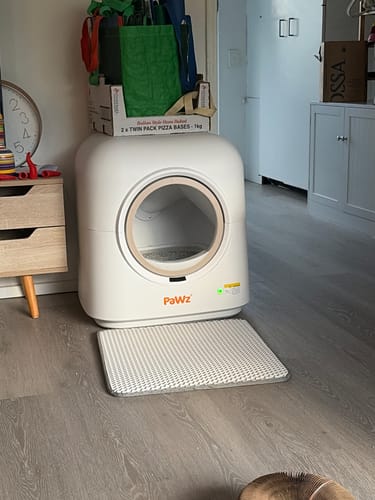 Customer's white AutoClean Pro automatic litter box in a room with the included litter mat placed in front.