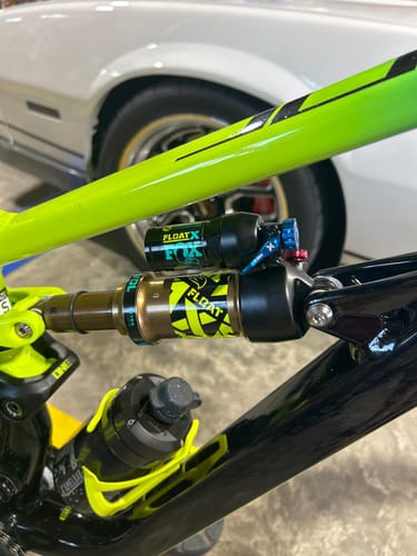 Close-up of a customer's yellow and black custom Fox Float X Decal on a rear shock of a bright green bike.
