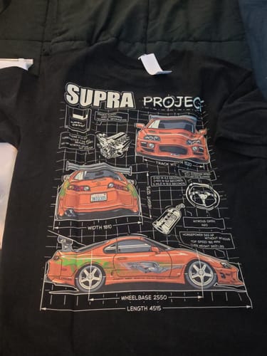Customer's black Supra Project T-shirt laid flat, showing the detailed orange car blueprint graphic.