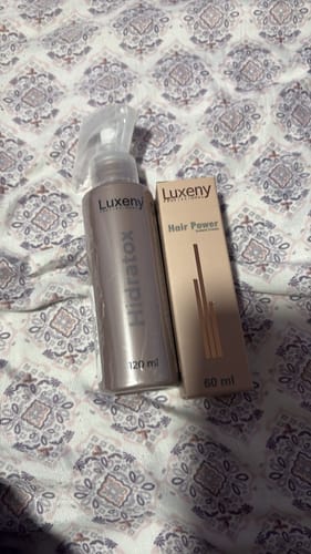 Una reseñadora muestra los productos para el cabello de su rutina, incluyendo el serum y un spray.