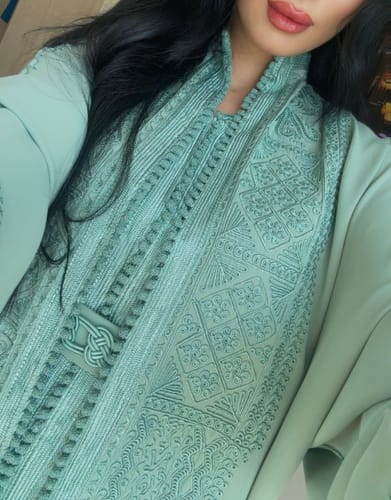 Close-up of a reviewer's mint Daur kaftan, showing the intricate embroidery on the chest and high collar.