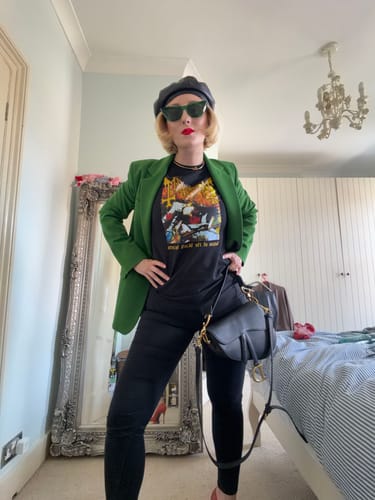 Reviewer wearing a black unisex t-shirt with a custom graphic print, styled with a green jacket.
