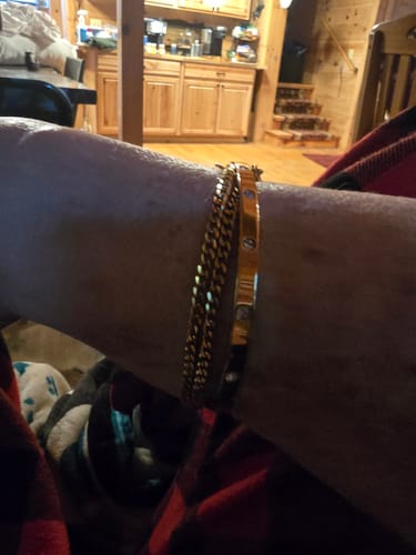 Close-up of a customer wearing the gold Vina Bracelet layered with two other bracelets on their wrist.