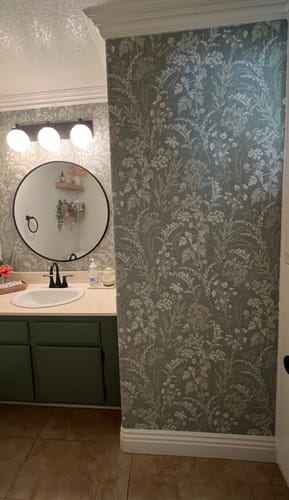 Customer's bathroom featuring the sage green and white floral Winsome Wallpaper on the walls, complementing a green vanity.