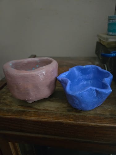 Customer shows two finished clay pots, one pink and one blue, made from the craft subscription box.