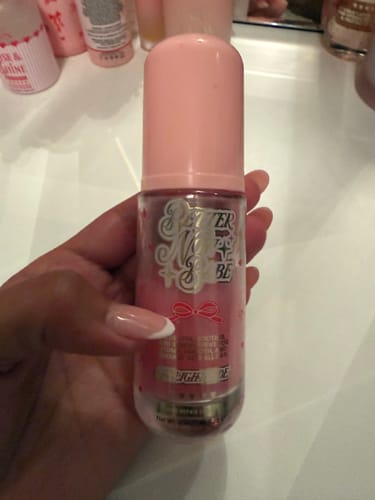 Reviewer holding the Better Now Babe Pink Barrier Repair Serum bottle, showing the pink formula inside.