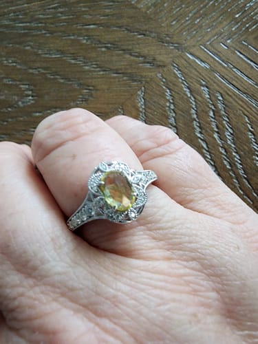 Close-up of a reviewer wearing the oval floral moissanite ring with a light-colored stone.