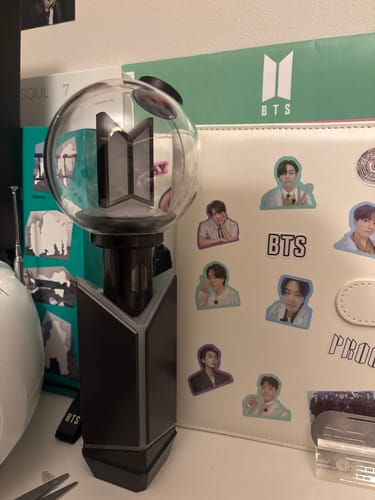 Customer's BTS Official Light Stick Ver.4 standing upright on a desk among other fan merchandise.