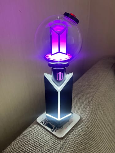 Customer's BTS Official Light Stick Ver.4 in its cradle, illuminated with a purple light.