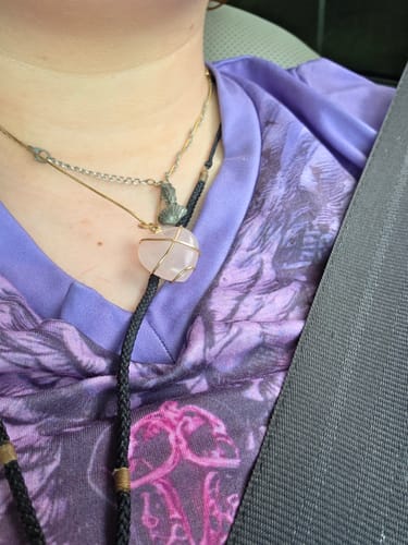 Customer wearing a wire-wrapped, heart-shaped Rose Quartz necklace from their monthly crystal subscription.
