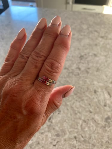Customer's hand wearing the silver Just Breathe Ring on the thumb over a mottled countertop.