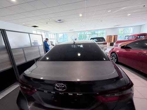 Customer's dark sedan in a showroom, showing the rear window with applied Terraflex Carbon Tint.