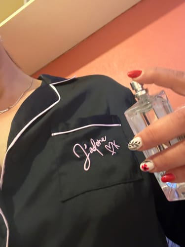 Reviewer applying the Inspired by J'adore - 417 perfume from its clear glass bottle onto a black shirt.
