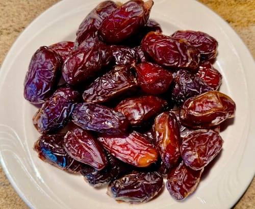 Customer's white plate piled high with soft, plump Organic Pitted Medjool Dates.