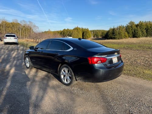A reviewer's dark sedan parked on a gravel road, showing the applied Terraflex Carbon Tint on the windows.