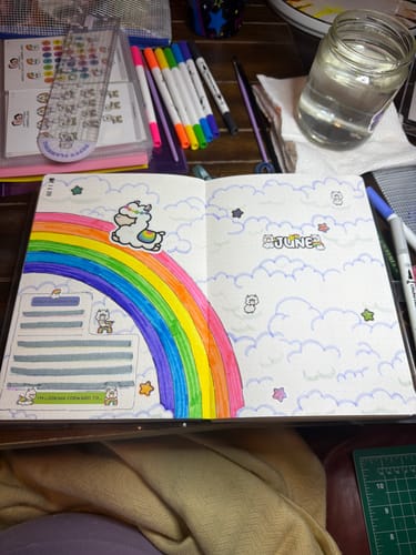 Customer's journal showing a monthly page for June decorated with a large rainbow and cute llama stickers.