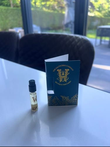 Reviewer's sample vial of Copacabana perfume next to its blue card holder on a white table.