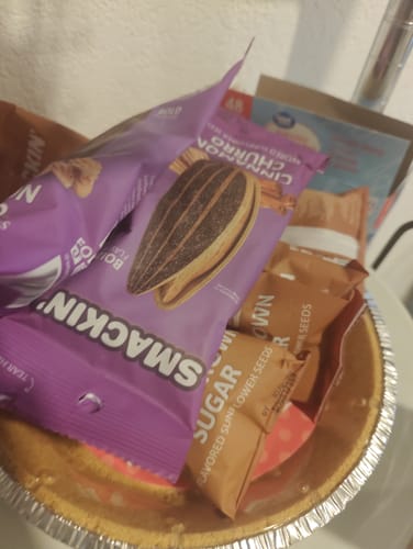 Reviewer's bucket containing various single-serving bags of Smackin' sunflower seeds.