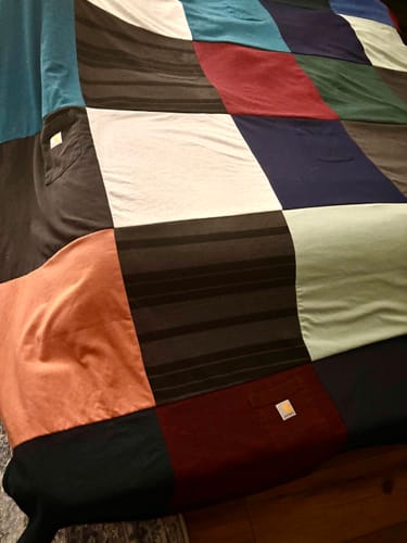 Customer's Project Repat T-Shirt Quilt made of colorful squares, draped over a piece of furniture.