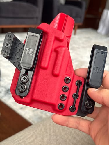 Customer holding a bright red XIPHOS ELITE holster with black clips and concealment wing.