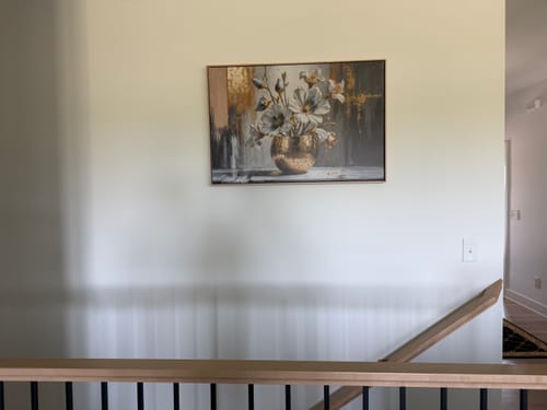 Customer's Magnolia Bloom in Gold Abstract Wall Art hanging on a wall above a staircase.
