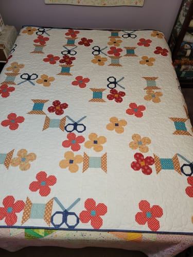 Customer's finished Snips and Blossoms quilt with a colorful pattern of scissors, thread spools, and flowers.