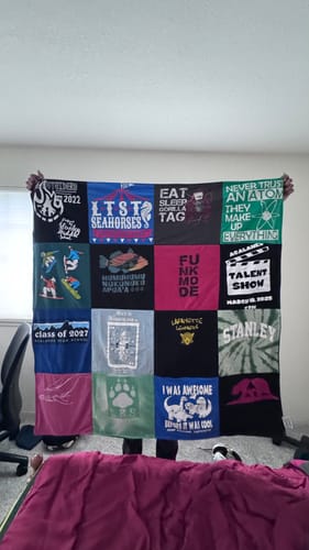 Customer holding up their large Project Repat T-Shirt Quilt, displaying a colorful grid of custom shirt panels.