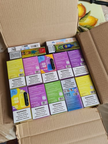 Kunde zeigt einen Lieferkarton, der mit zahlreichen bunten Verpackungen des RANDM TORNADO 20000 gefüllt ist.