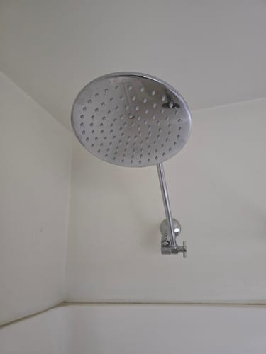 Reviewer's chrome 8 Inch Rain Shower Head and Adjustable Shower Arm installed in a white shower.