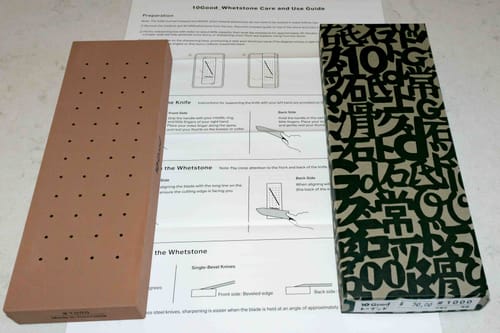 Customer's 10Good #1000 whetstone shown out of its box with the user guide laid out behind it.