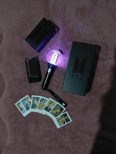 Customer's illuminated BTS Official Light Stick Ver.4 displayed with its packaging and a fan of photo cards.
