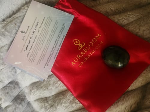 Customer displays the Crystal Comfort Card Deck card, a dark crystal, and a red pouch on a furry surface.
