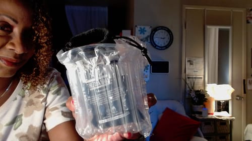 Reviewer shows the Absolute Crystal Glow perfume in its protective inflatable packaging.