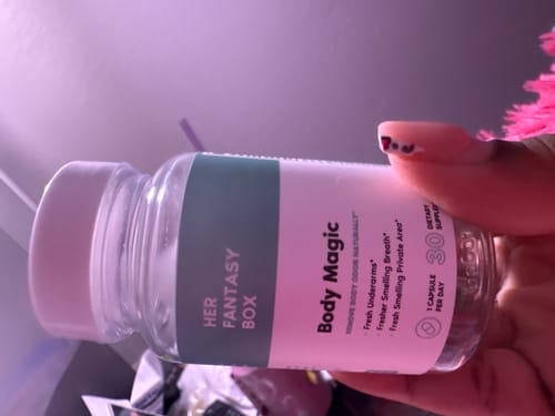 Customer holding the clear bottle of Body Magic chlorophyll pills, showing the label.