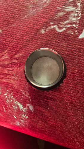 Reviewer's espresso paper filter placed inside a metal portafilter basket on a textured red surface.