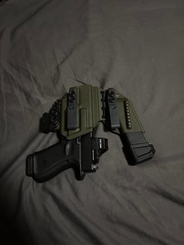 Customer's olive green AXIS ELITE holster holding a pistol and spare magazine on a dark surface.