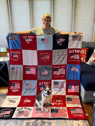 A reviewer holds up their finished Project Repat T-Shirt Quilt made from many American flag t-shirts.