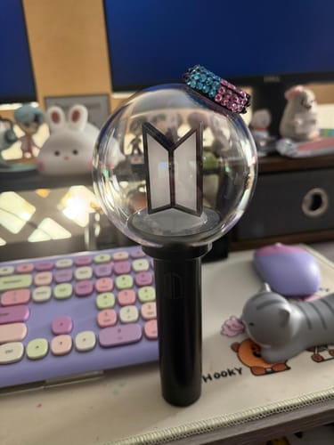 Customer's BTS Official Light Stick Ver.4 on a desk, customized with a sparkly pink and blue band on the dome.