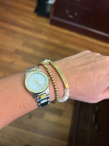 Reviewer showing the Gold Accent Bracelet on their wrist, worn with a watch and a second engraved bracelet.