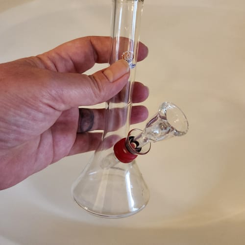 A reviewer holds the small, clear glass Classic Round Beaker Water Pipe in their hand.
