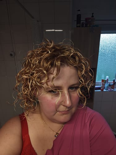 Klant met gedefinieerde, blonde krullen na gebruik van Curl Bites shampoo.