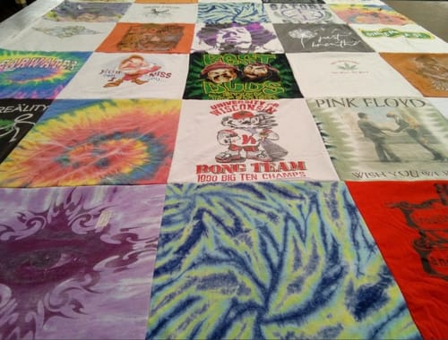 A customer's Project Repat T-Shirt Quilt laid out, featuring colorful and vintage hippie-themed shirts.