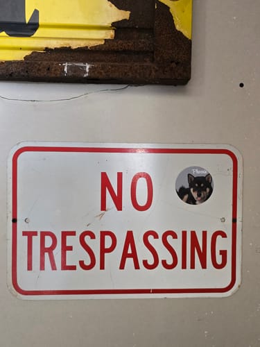 Customer's custom sticker of their puppy placed on a white 'No Trespassing' sign.