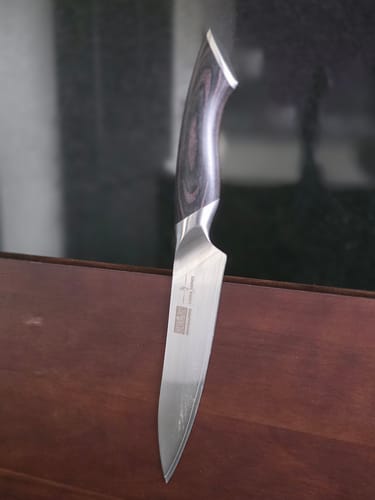 Customer's close-up of a knife from the chef set, showing the dark pakkawood handle and shiny steel blade.