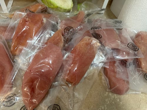 Customer's multiple vacuum-sealed packages of Organic Chicken Breasts spread out on a surface.