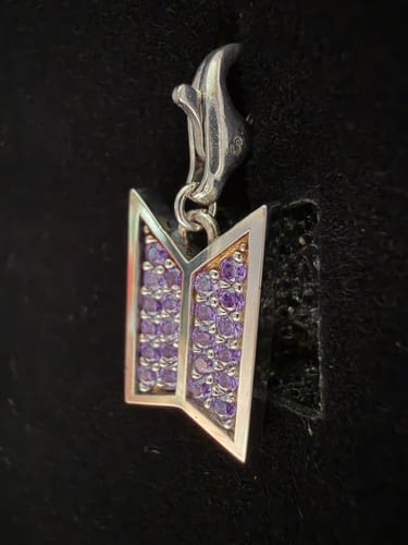 Reviewer's close-up of the silver BTS charm, showing its sparkling purple stones.