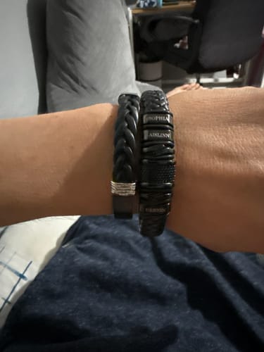 A customer wearing the black bracelet on their wrist, showing the personalized name engravings.