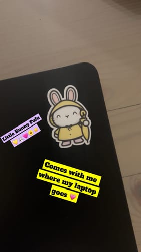Customer's Rain Bunnies sticker, a cute bunny in a yellow raincoat, applied to a black laptop.