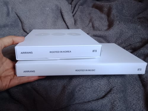 Customer holding the two stacked, white album boxes from the BTS ARIRANG 5TH ALBUM STANDARD SET.